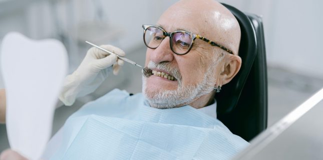 A man sat in a dentist's chair having his teeth examined